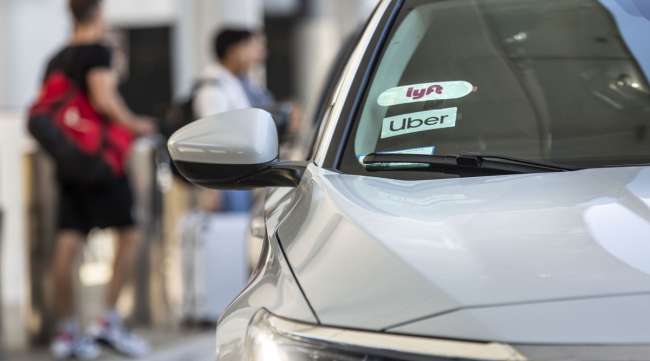Lyft and Uber badges are displayed on the windshield of a vehicle.