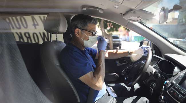 A driver in Los Angeles adjusts his face mask as Uber and Lyft drivers conduct a "caravan protest" outside the California Labor Commissioner's office April 16.