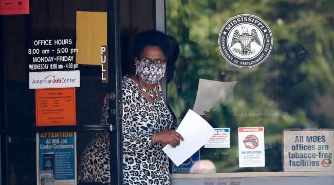 A masked worker at a WIN job center in Pearl, Miss., holds an unemployment benefit application form as she waits for a client on April 21.