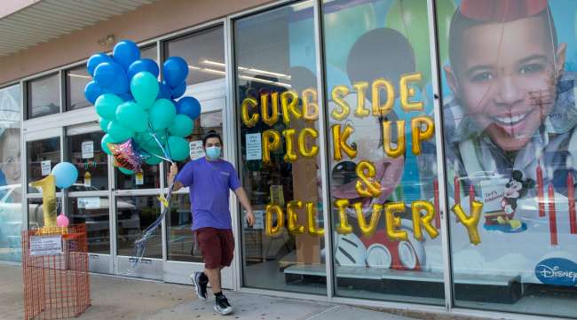 A Party City employee delivers balloons to a customer curbside in Oceanside, N.Y., on May 27.