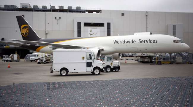 A delivery van passes in front of a cargo jet parked on the tarmac at a UPS Worldport facility in Louisville, Ky., on Jan. 28.