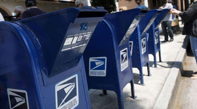A customer deposits mail into a USPS mail collection box outside a post office in Burbank, Calif.