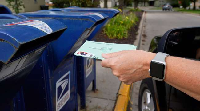 A person drops applications for mail-in ballots into a mailbox in Omaha, Neb., on Aug. 18.