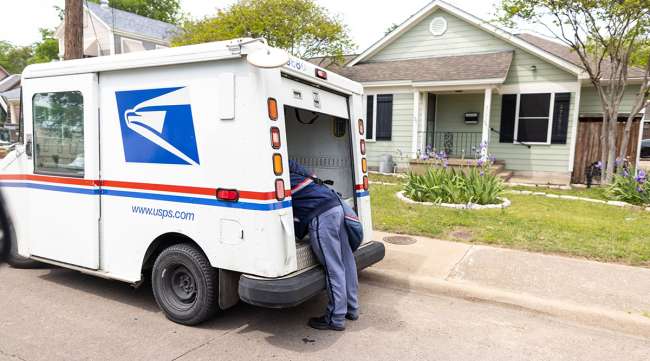 A postal service worker works out of the back of his truck