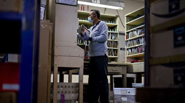 A letter carrier prepares mail for delivery at a USPS facility in Virginia.