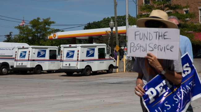 USPS trucks sit as demonstrators march outside of a post office in Royal Oak, Mich., on Aug. 22.