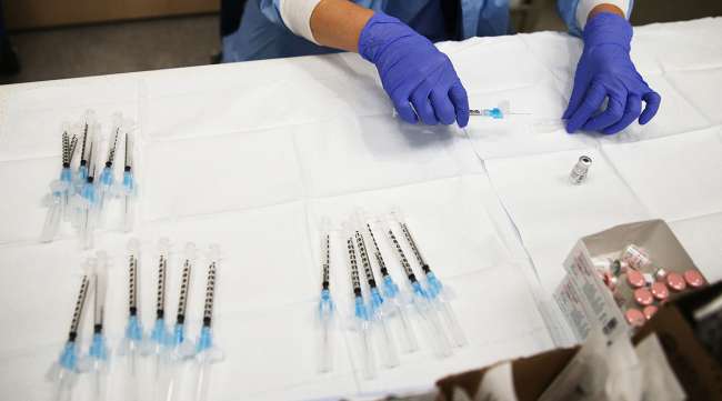 A pharmacy technician prepares a dose of the COVID-19 Pfizer vaccine.