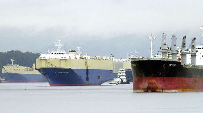 A tugboat maneuvers through waiting freighters on the Columbia River near the Port of Vancouver in Vancouver, Wash.