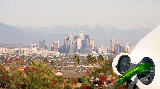 Getty Image of electric vehicle charging with Los Angeles as a backdrop