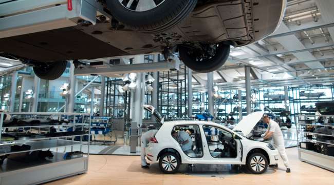 Employees work on an electric automobile on the assembly line of a Volkswagen AG factory in Germany.