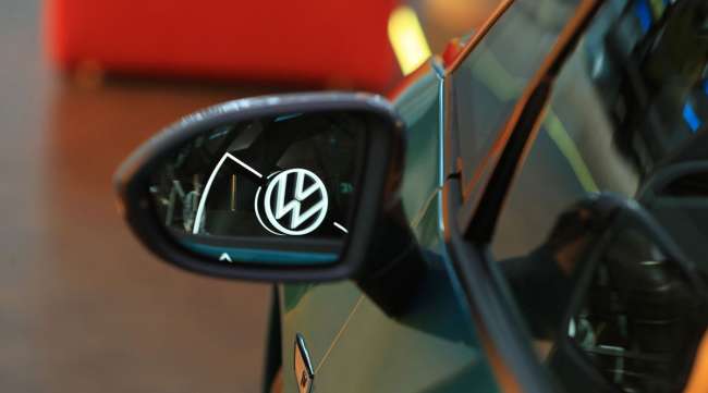 A VW logo is reflected in the wing mirror of a VW ID electric automobile.