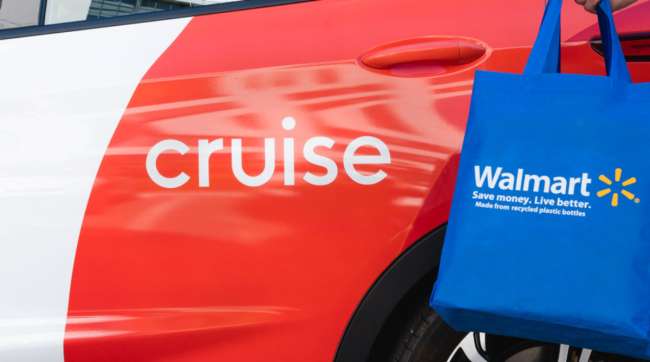 A Cruise autonomous vehicle is seen with a Walmart-branded bag outside it.