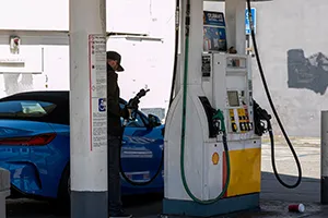 A customer holds a fuel nozzle at a Shell gas station