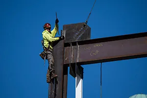 An ironworker guides a beam during construction of a municipal building