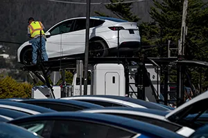 A worker delivers vehicles to a Tesla store