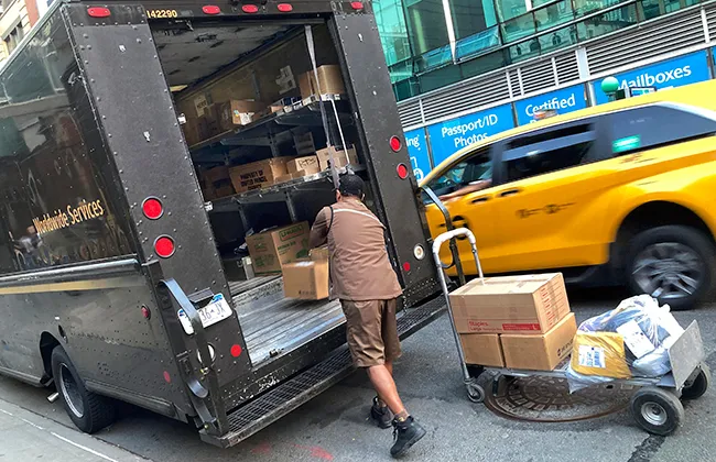 A UPS driver loads his truck near a UPS store in New York City