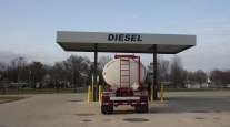 A tanker truck sits parked at a diesel fuel pump