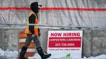 A worker passes a hiring sign