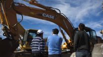 Customers inspect heavy digging machinery at a 2012 Ritchie Bros. auction