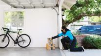 An Amazon deliveryperson places a package inside a customer's garage