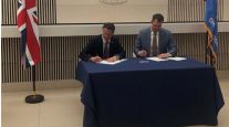 Kevin Stitt and Nigel Huddleston sign the MOU