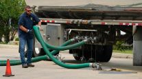 Tank truck driver connects hose to storage tank