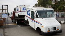 USPS mail trucks arrive on a tow truck to a post office in California in August 2020. (Patrick T. Fallon/Bloomberg News)