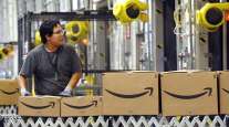 An Amazon worker watches as boxed merchandise moves along a conveyor be