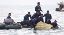 Indonesian Navy divers pull out airplane pieces during a search operation for the Sriwijaya Air passenger plane.