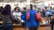 An employee wearing a protective mask assists customers at a department store in Georgia.