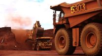 An excavator loads ore into an autonomous dump truck. (Bloomberg News)