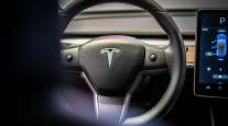 Tesla logo on steering wheel of Tesla Model 3 vehicle.