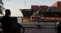 People watch as a cargo ship and tug boat travel into the Port of Savannah. (Ty Wright/Bloomberg News)