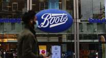 A pedestrian wearing a protective facemask passes a Boots pharmacy in London