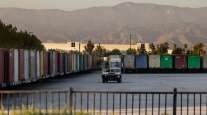 A worker moves shipping containers outside a warehouse in Redlands, Calif.