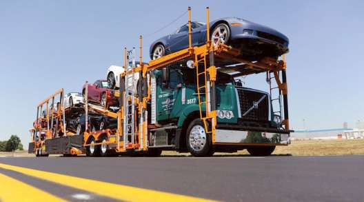 A Jack Cooper truck transports cars down a highway.
