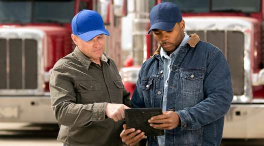 Two truck drivers having a meeting using a tablet computer.