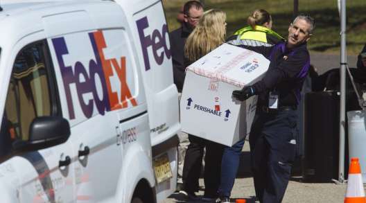 A FedEx employee carries a box before loading into a van at a coronavirus testing facility in New Jersey.