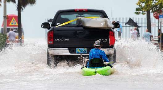  A truck pulls a man on a kayak after flooding in Key West, Fla. 