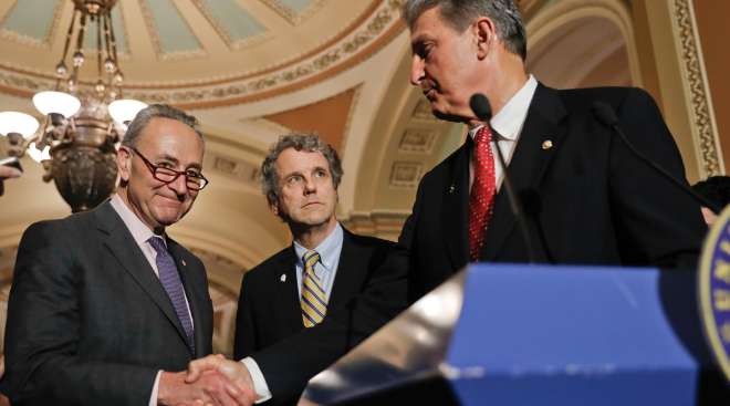 Senate Majority Leader Charles Schumer (D-N.Y.), left, shakes hands with Sen. Joe Manchin (D-W.Va.), right, accompanied by Sen. Sherrod Brown (D-Ohio) while speaking with reporters on Capitol Hill in Washington.