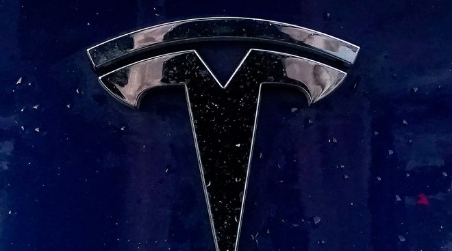 A Tesla emblem is affixed to a passenger vehicle