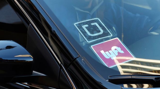 A ride share car displays Lyft and Uber stickers