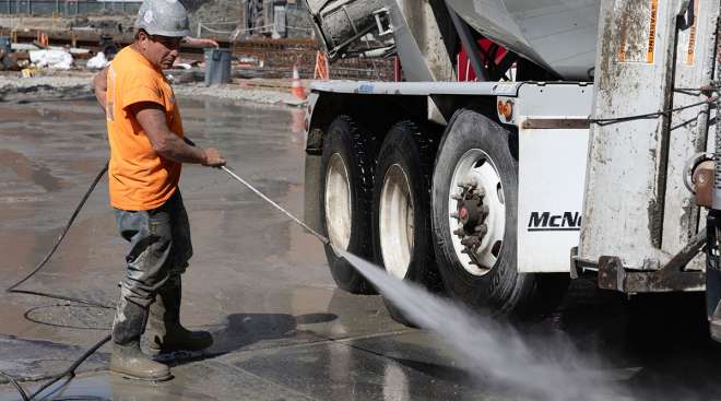worker cleans cement truck
