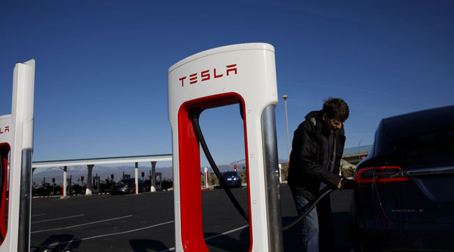 A driver unplugs a charging plug from a Tesla Model X vehicle in Lebec, Calif.